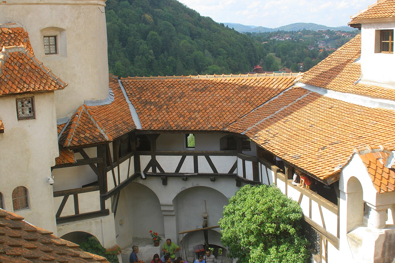 Curtea deschisă privită în jos de pe un nivel superior al castelului; galerie și acoperișuri. Nu este fotografie aeriană.