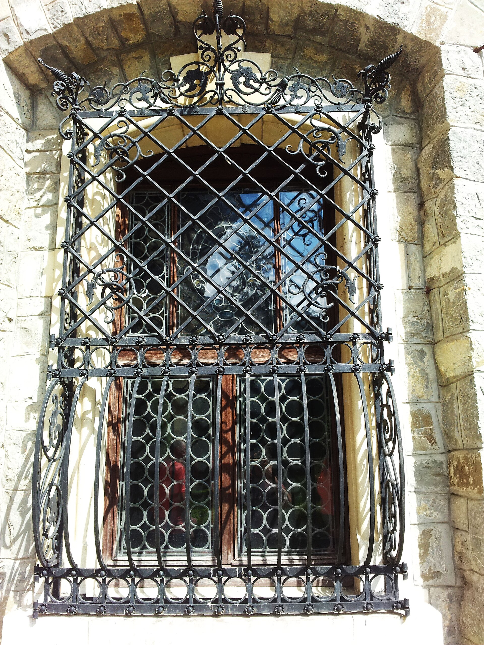 Fereastră cu ancadrament sculptat și grilaj metalic.