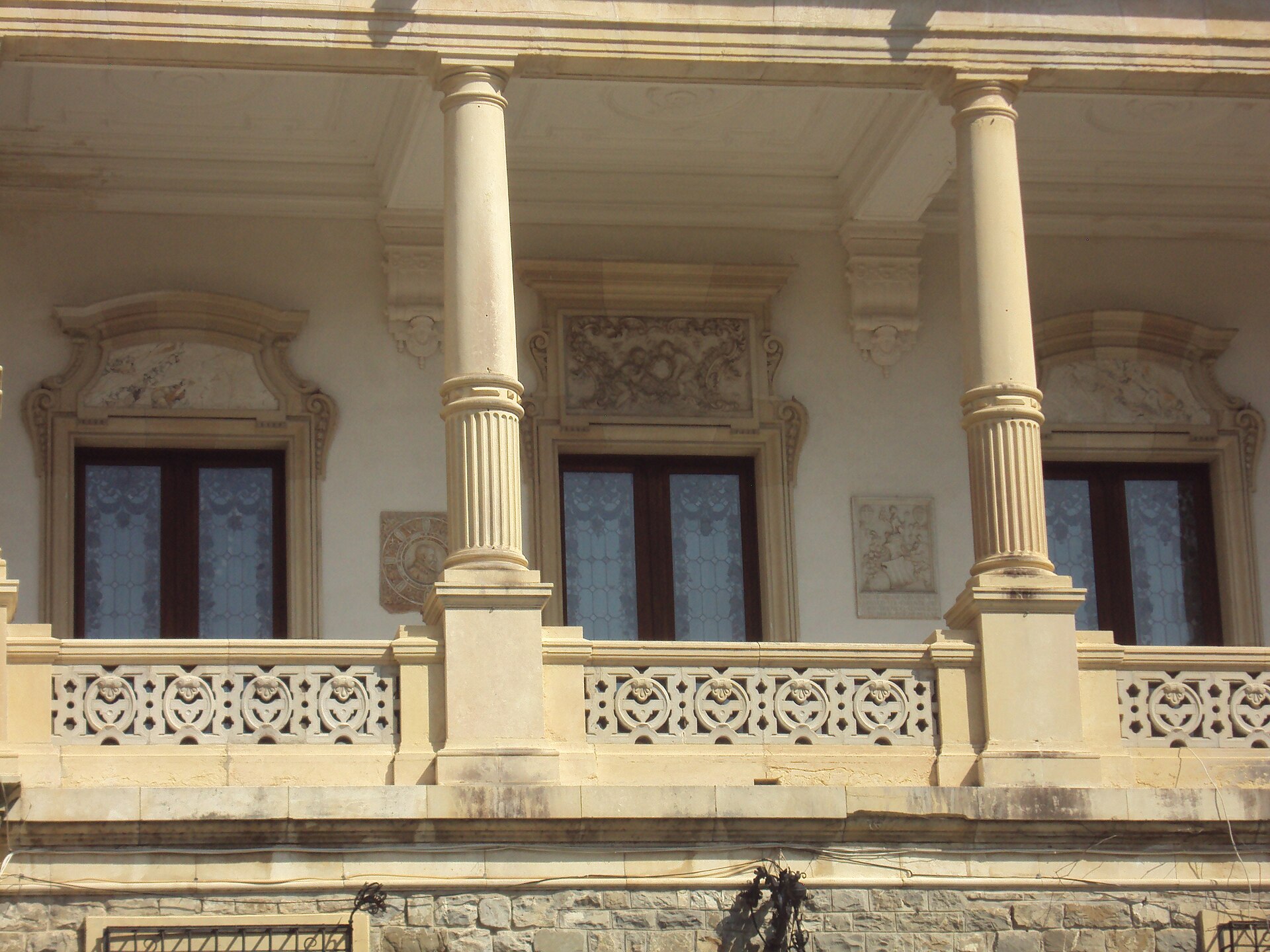 Loggie exterioară cu coloane, parapet sculptat și plafon.