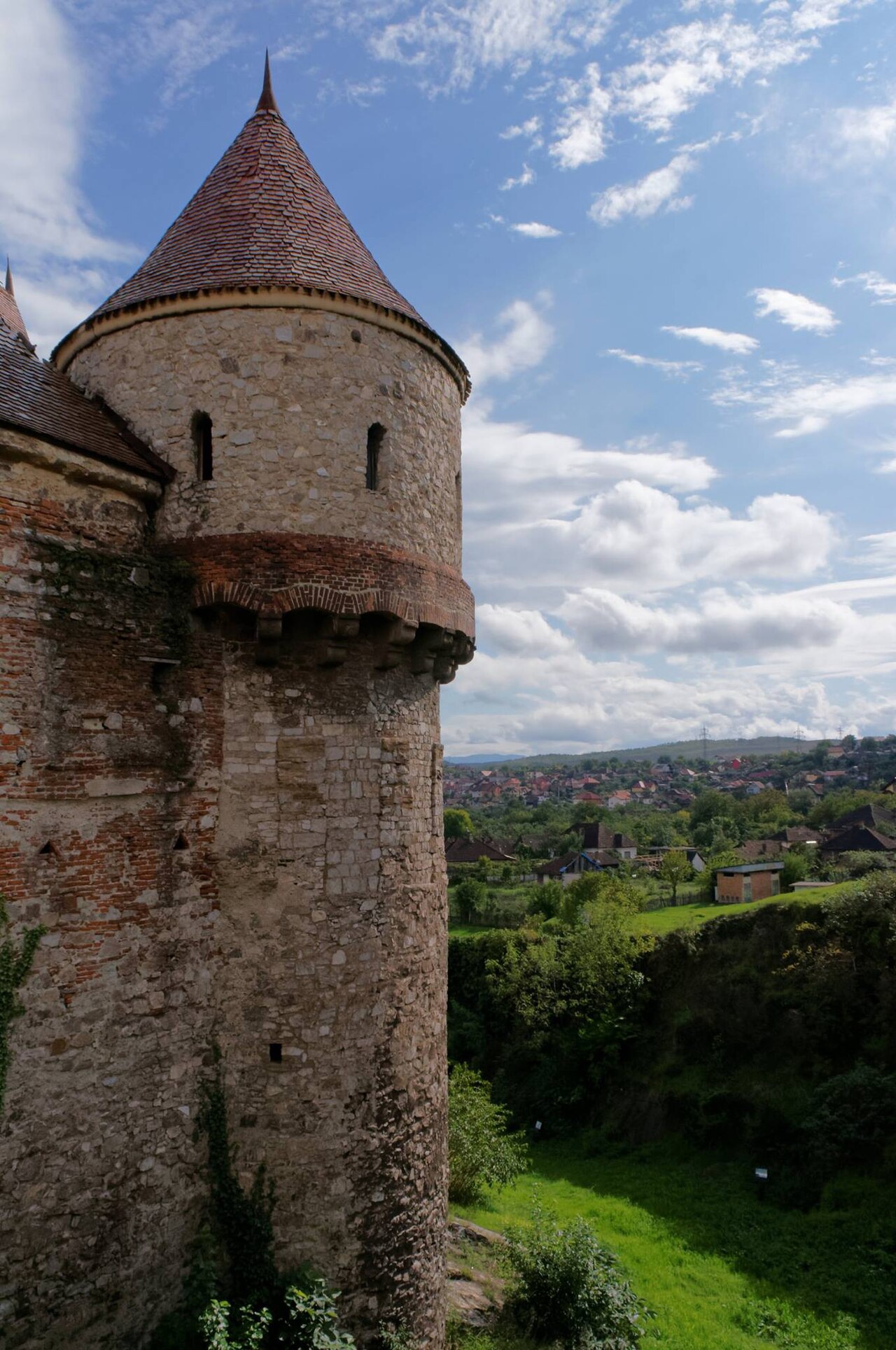 Turn circular exterior privit oblic, cu corp cilindric, console și acoperiș conic.