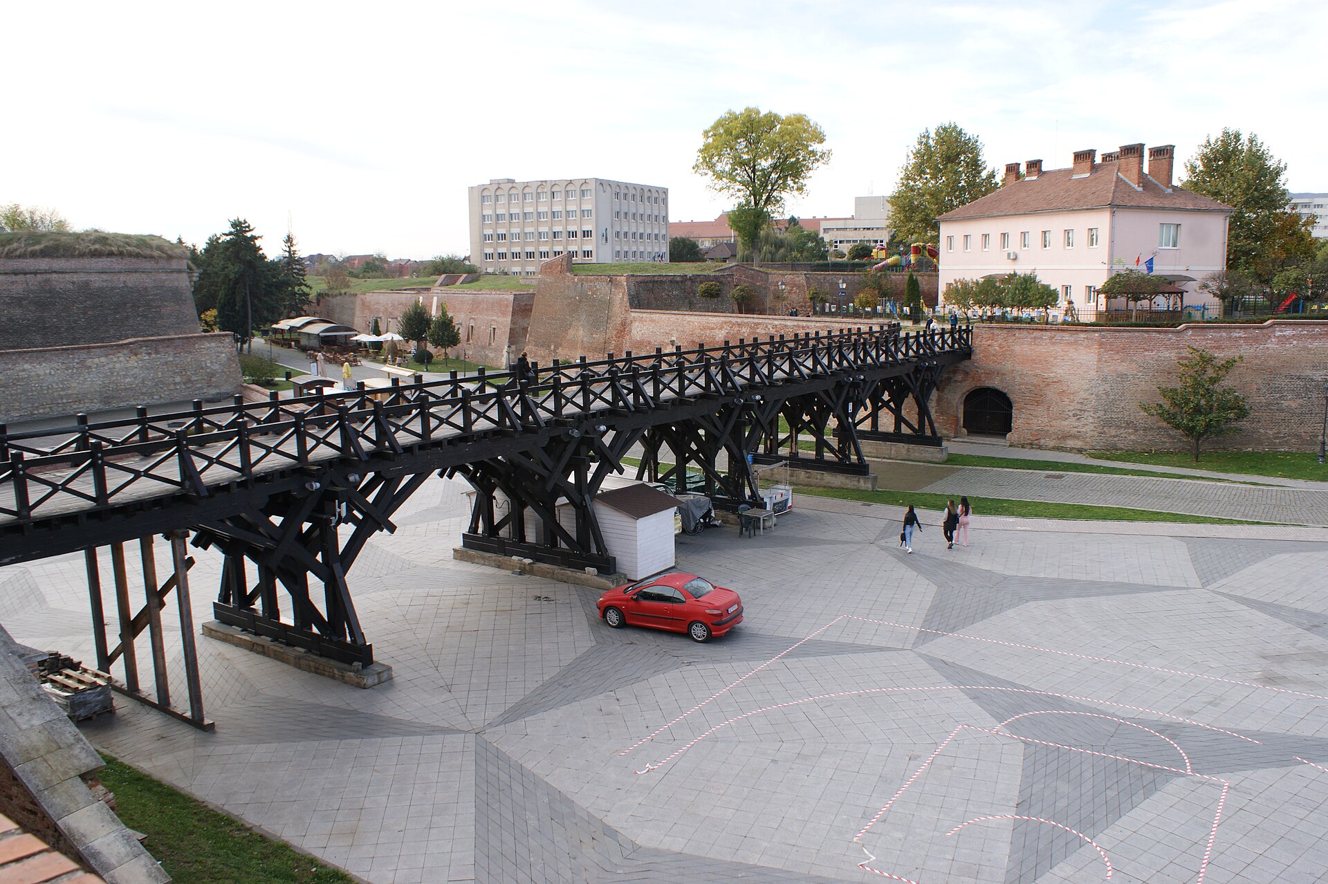 Pod de lemn cu triunghiuri portante, văzut lateral din șanț.