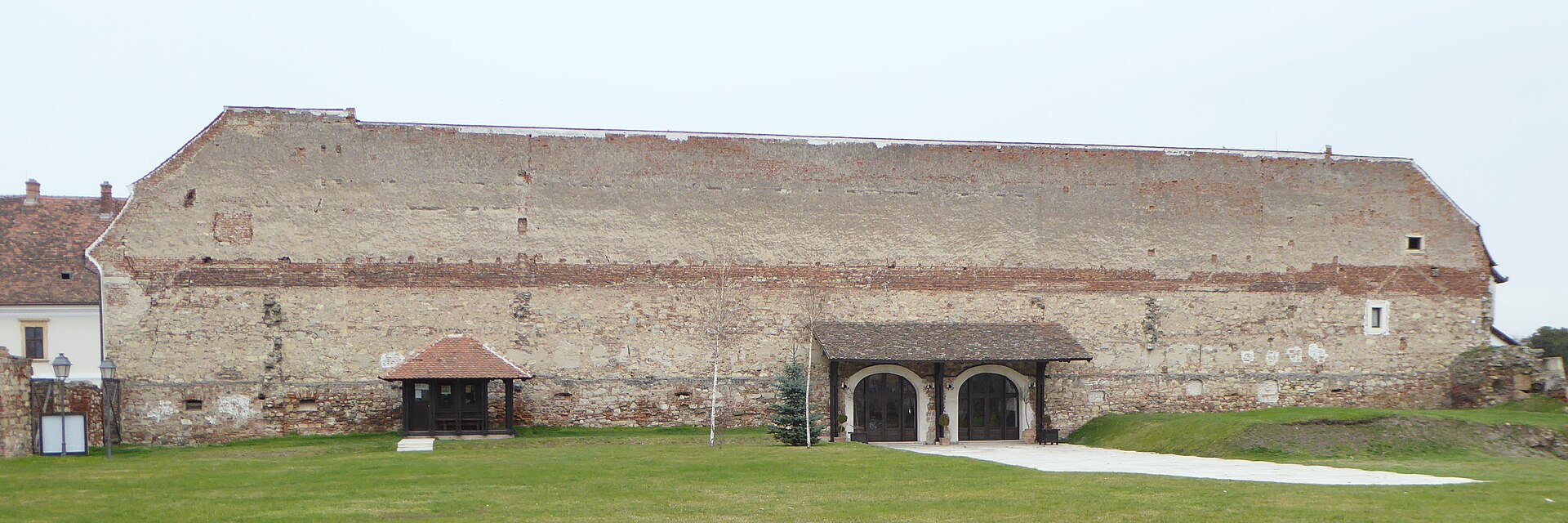Exteriorul clădirii joase din bastion, cu acoperiș lung și portaluri.