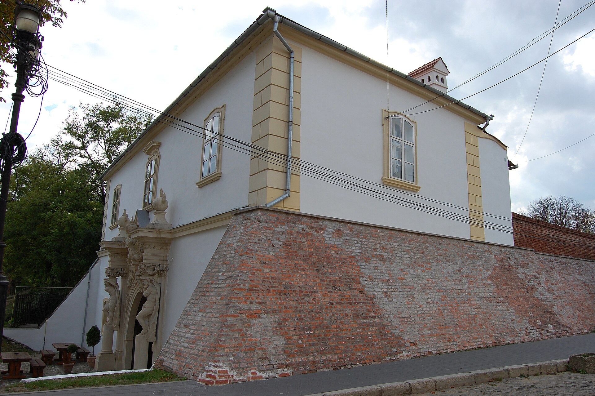 Poarta IV din lateral: volumul clădirii, zidul bastionar și acoperișul.