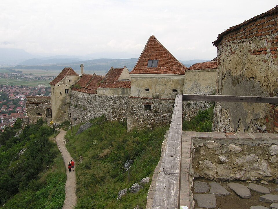 Racordul dintre zidurile înalte, stâncă și aleea de acces în pantă.