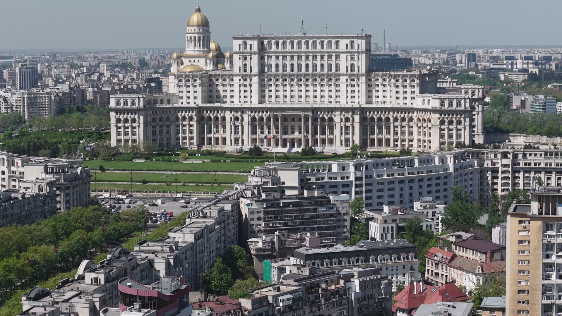 Perspectivă aeriană oblică asupra fațadei principale și retragerilor în trepte; Catedrala apare separat în fundal. Imaginea este fotografia-poster furnizată de Pexels pentru videoclip, nu un cadru extras local.