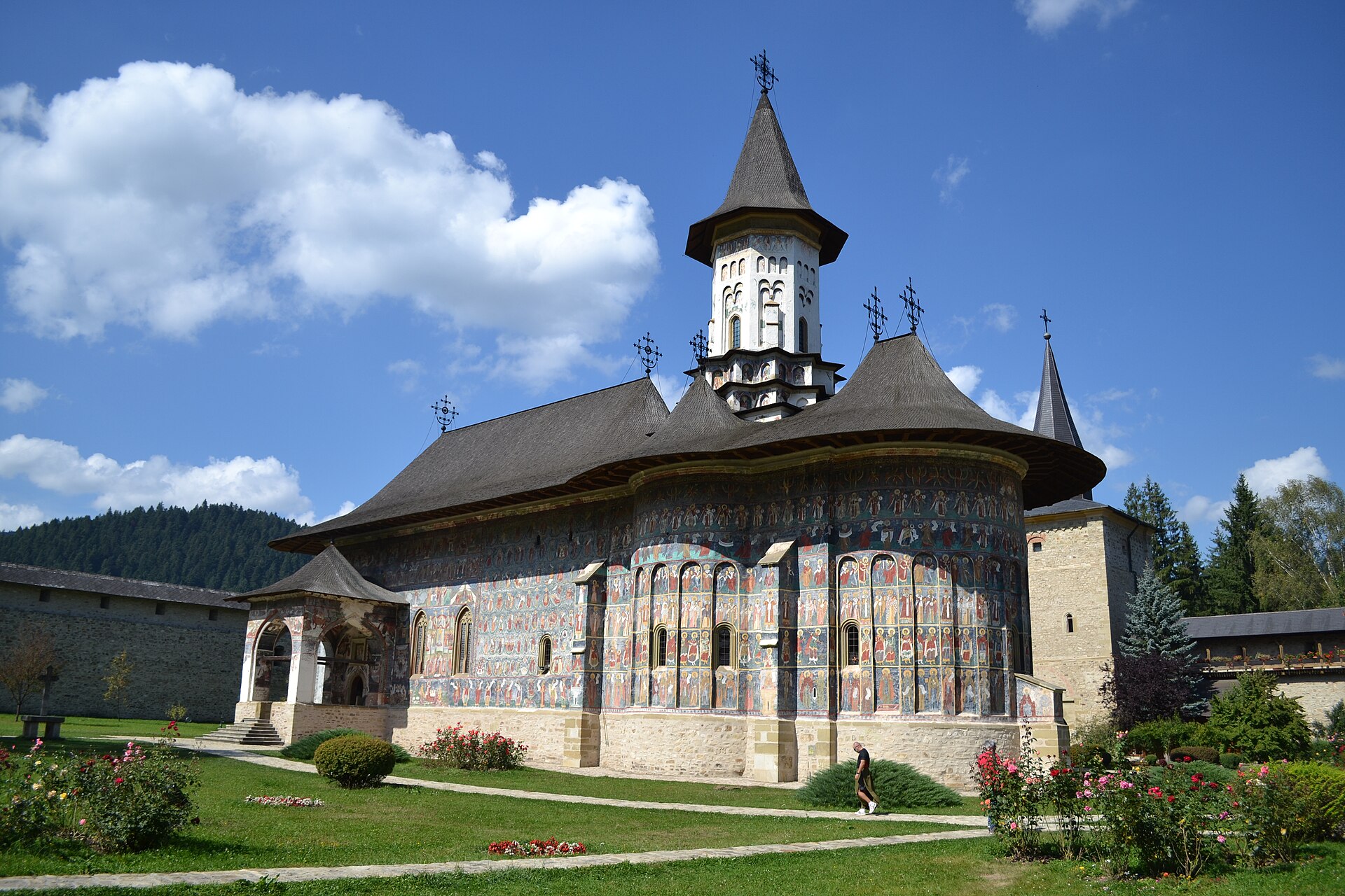 Biserica dinspre zona absidală: acoperiș profilat, turlă și fațadă pictată