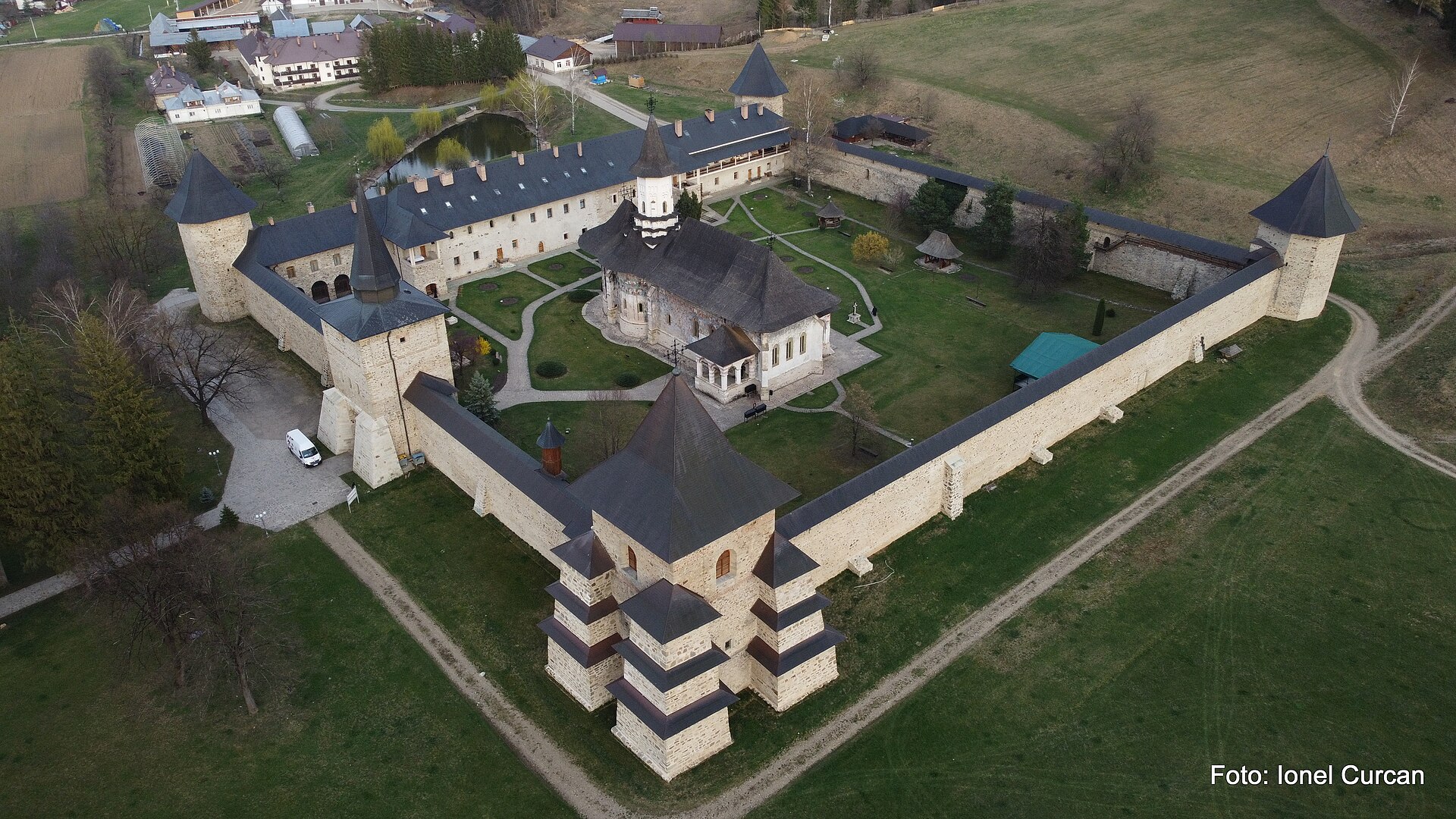 Vedere aeriană oblică apropiată de turnul masiv: ziduri, curte și acoperișurile ansamblului