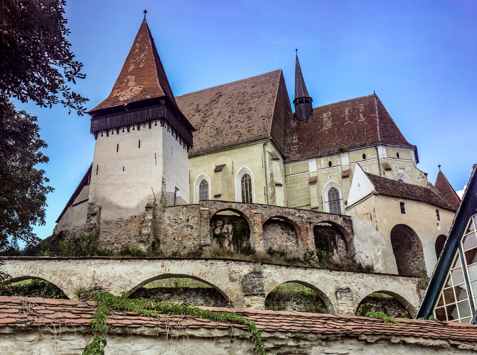 Biserica, turnul și zidurile cu arcade, perspectivă joasă apropiată
