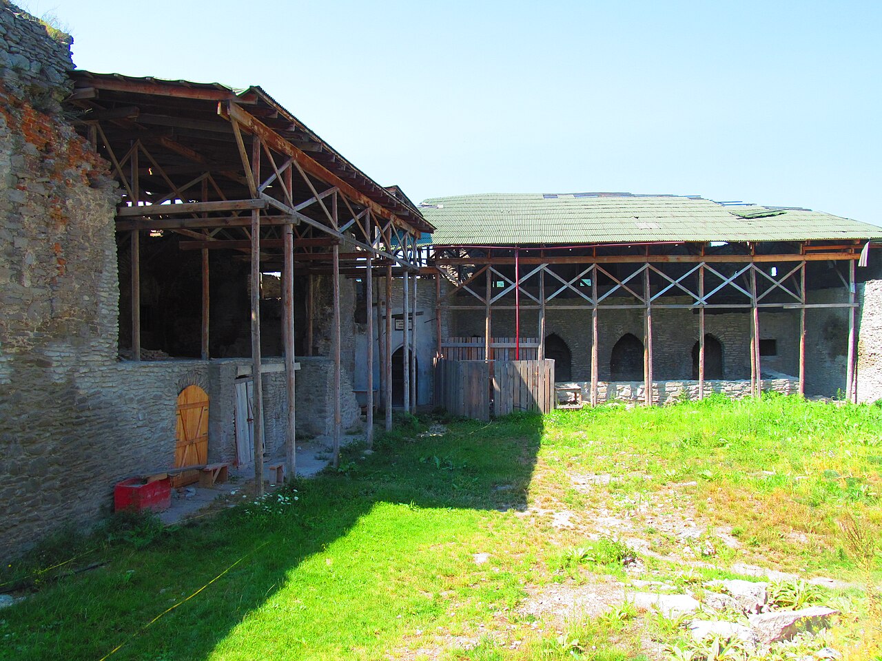 Curte înierbată între ziduri și schele de restaurare