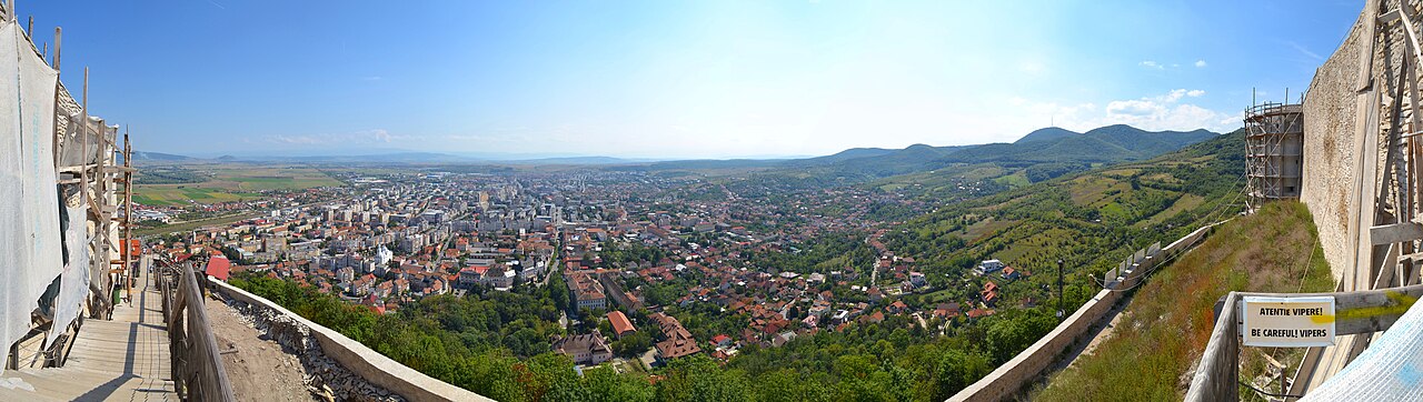 Panoramă de la înălțimea cetății; margini de zid și orașul în fundal