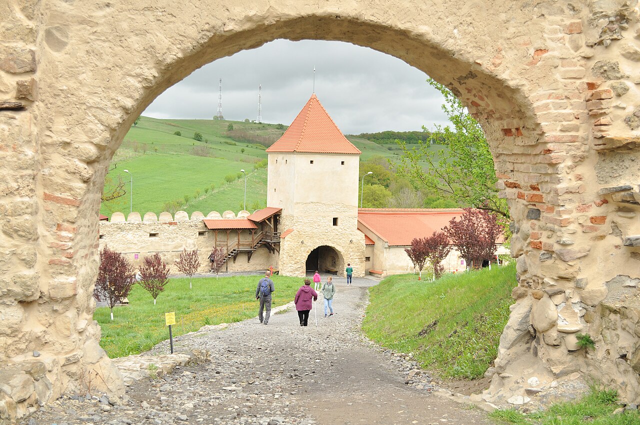 Portal arcuit din piatră care încadrează curtea și turnul cu acoperiș