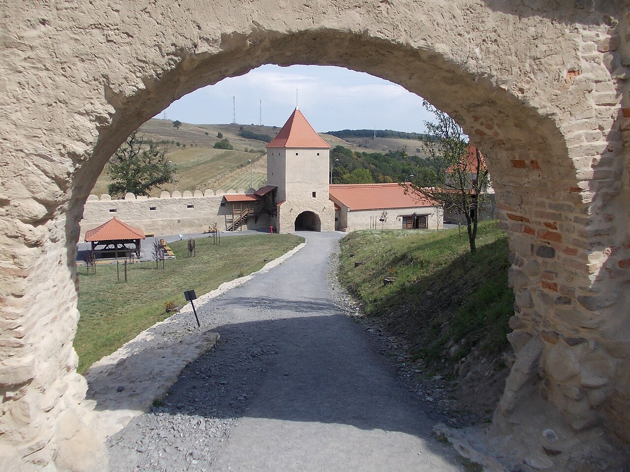 Poartă arcuită din piatră privită spre curtea inferioară și anexe