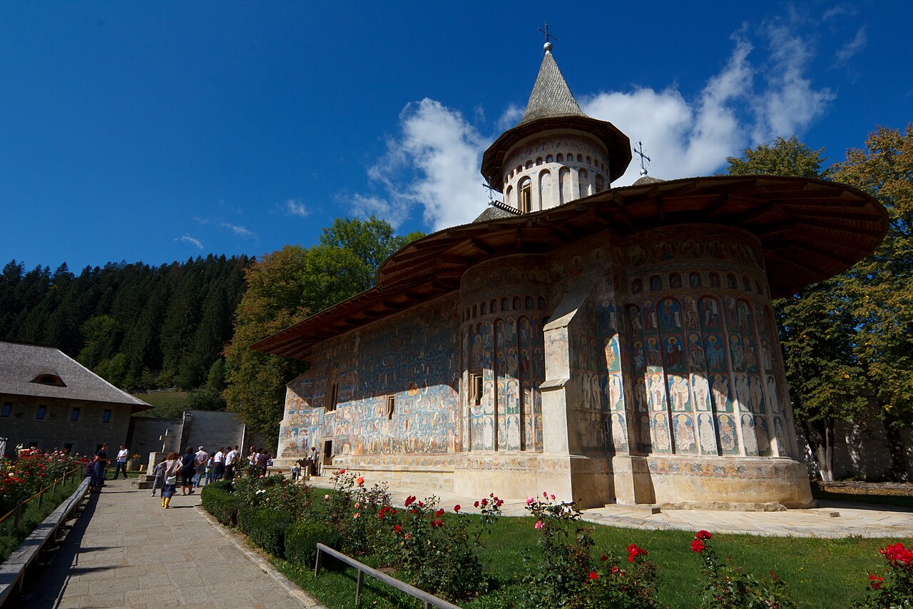 Biserica pictată și turla, văzute oblic din curte.