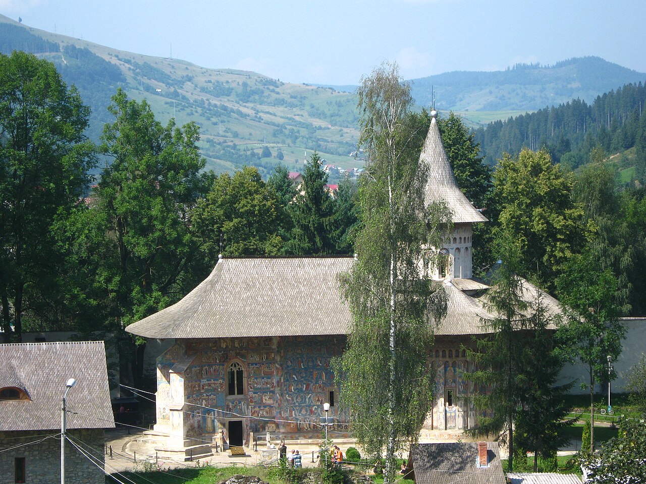 Biserica văzută dintr-un punct ridicat; arborii ascund parțial corpul.