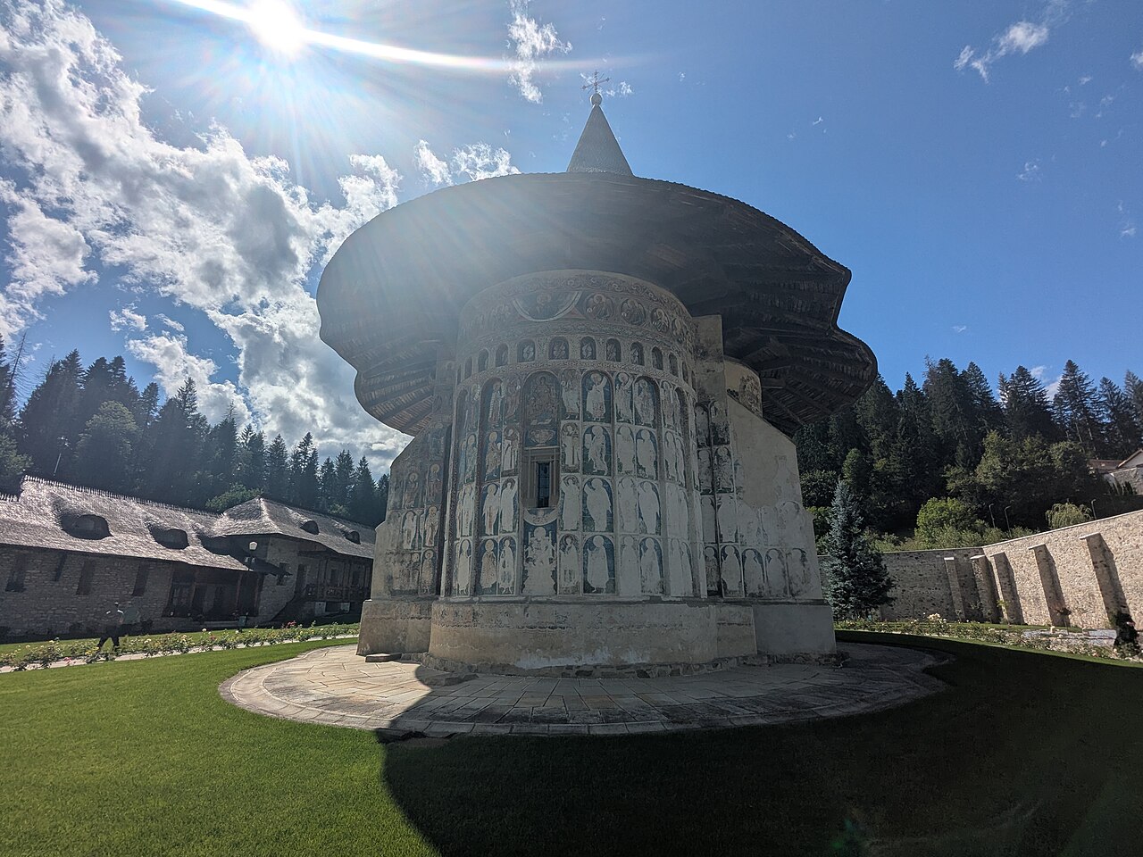 Capătul absidal, soclul și streașina largă, văzute din curte.
