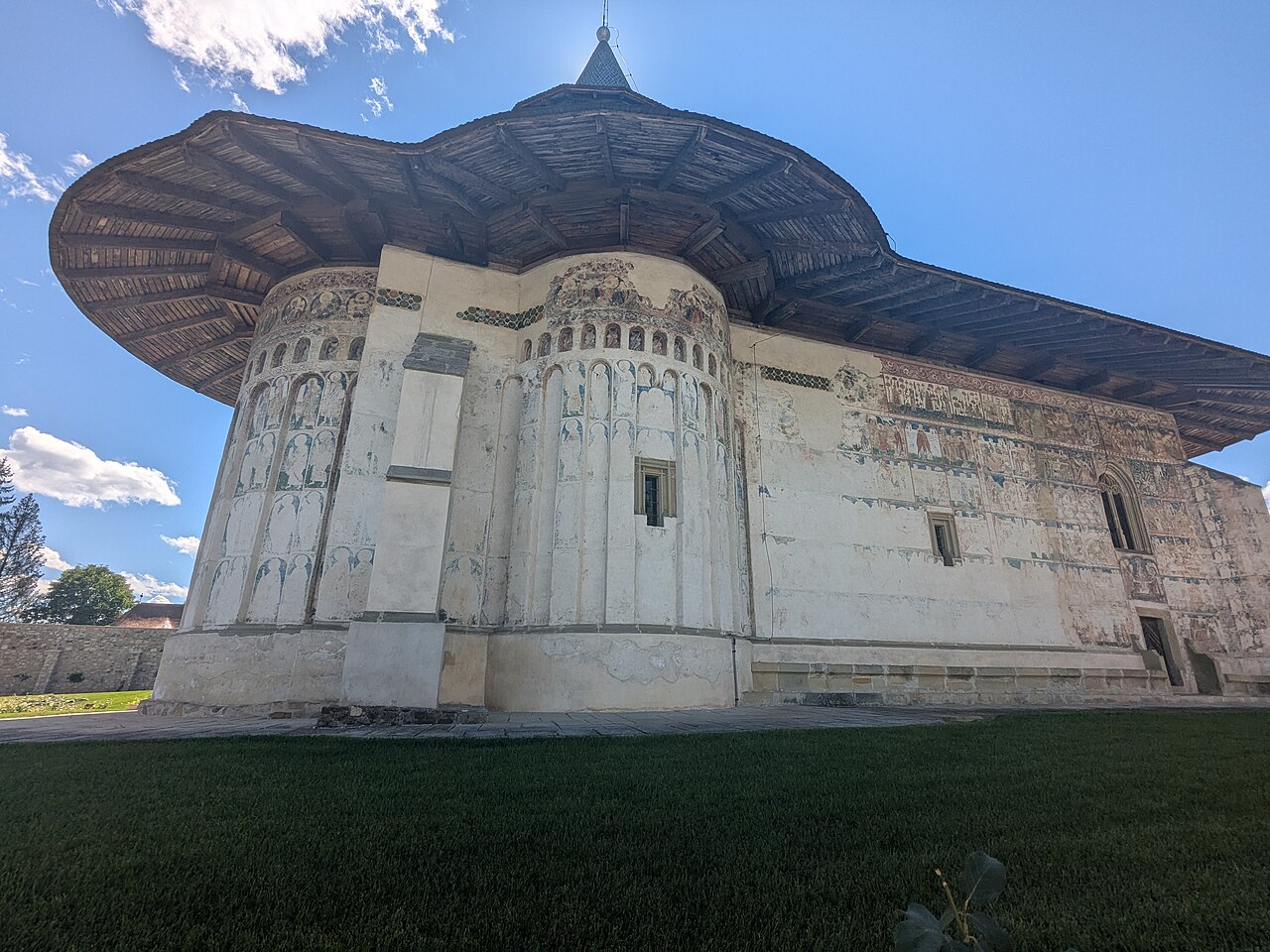 Fațada cu pictură exterioară păstrată fragmentar, absidă și ferestre.