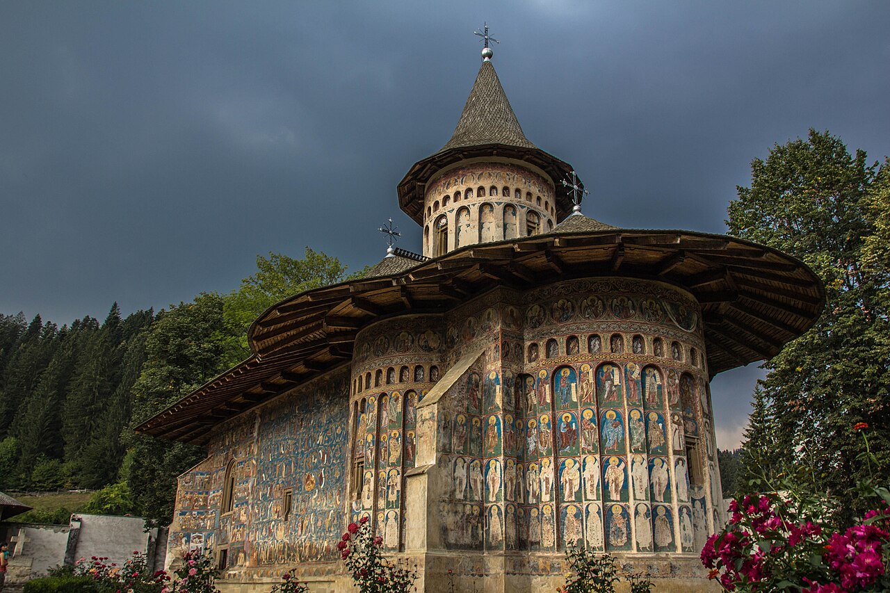 Biserica și turla dinspre capătul absidal, cu fațada pictată alăturată.