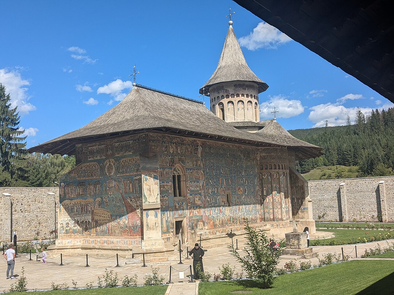 Biserica din curte: pereți pictați, soclu, turlă și zidul alăturat.