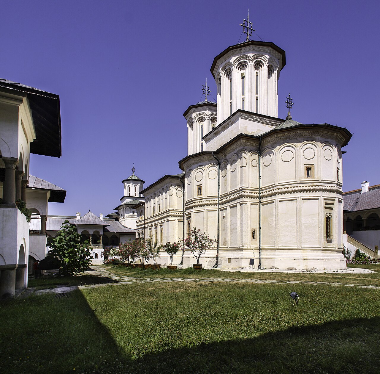 Fațada lungă și absida laterală a bisericii, cu turlele deasupra.
