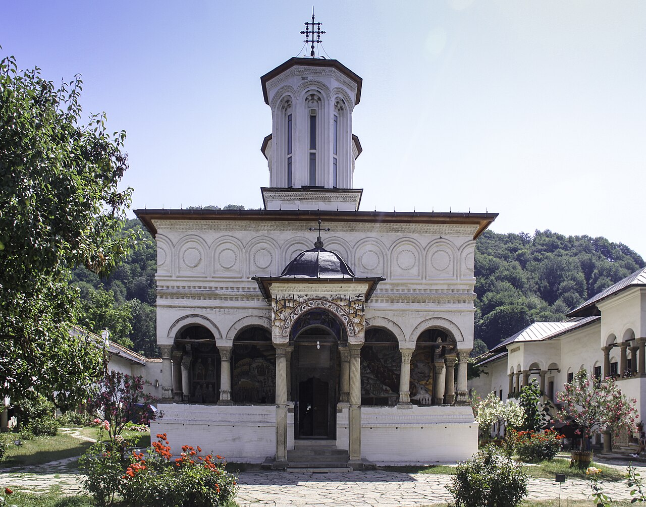Pridvorul bisericii văzut frontal, cu coloane, arcade și pictură.