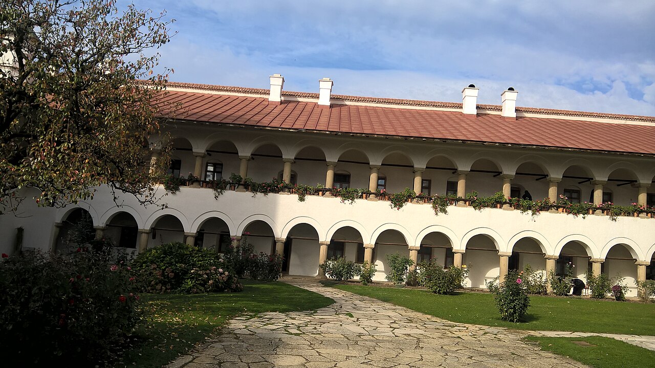Fațada lungă cu arcade și coșuri deasupra învelitorii.