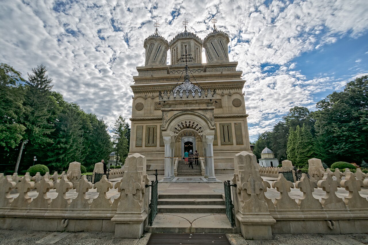 Fațada de intrare și treptele soclului, cu împrejmuirea sculptată.