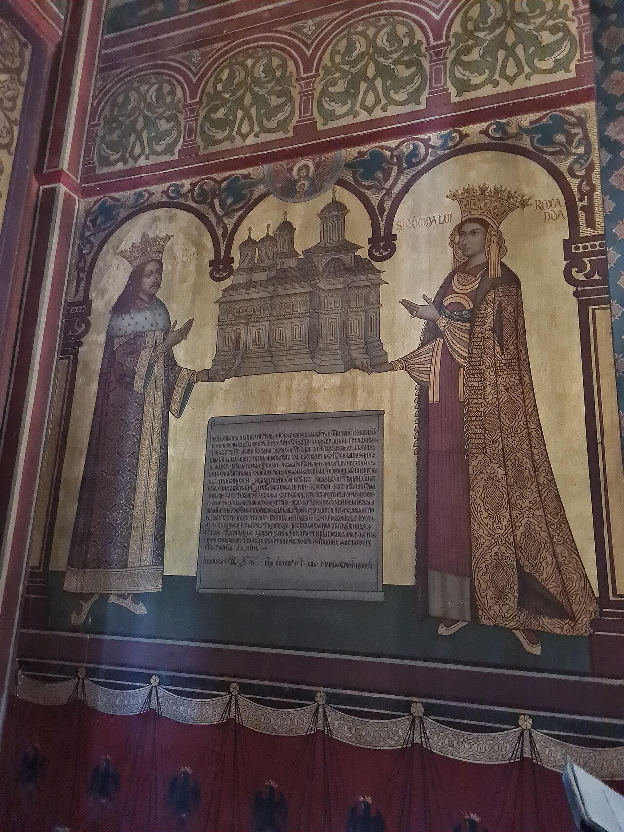 Pictură murală din interior, cu panou și soclu decorat.
