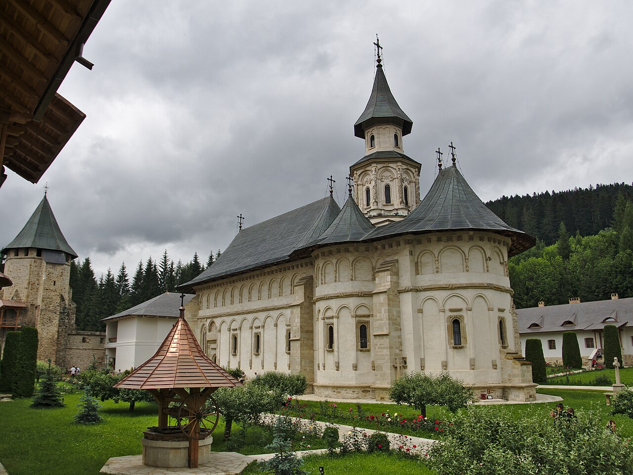 Biserica dinspre capătul absidal, cu fațada lungă și curtea.