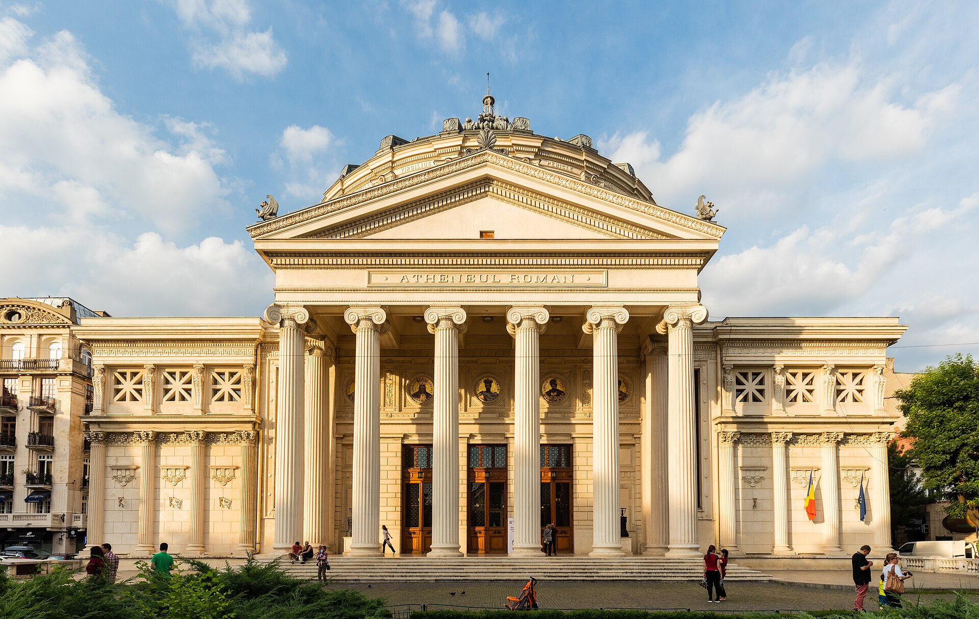 Portic frontal larg, cu scări, coloane, fronton și corpurile laterale