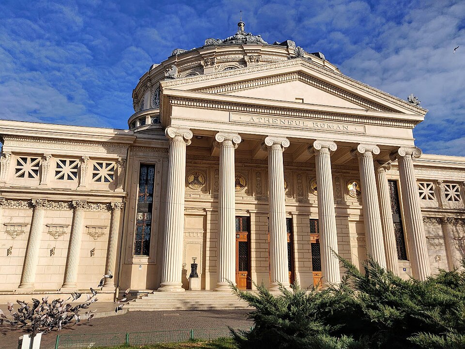 Portic din unghi complementar, cu fronton, capiteluri și corp lateral