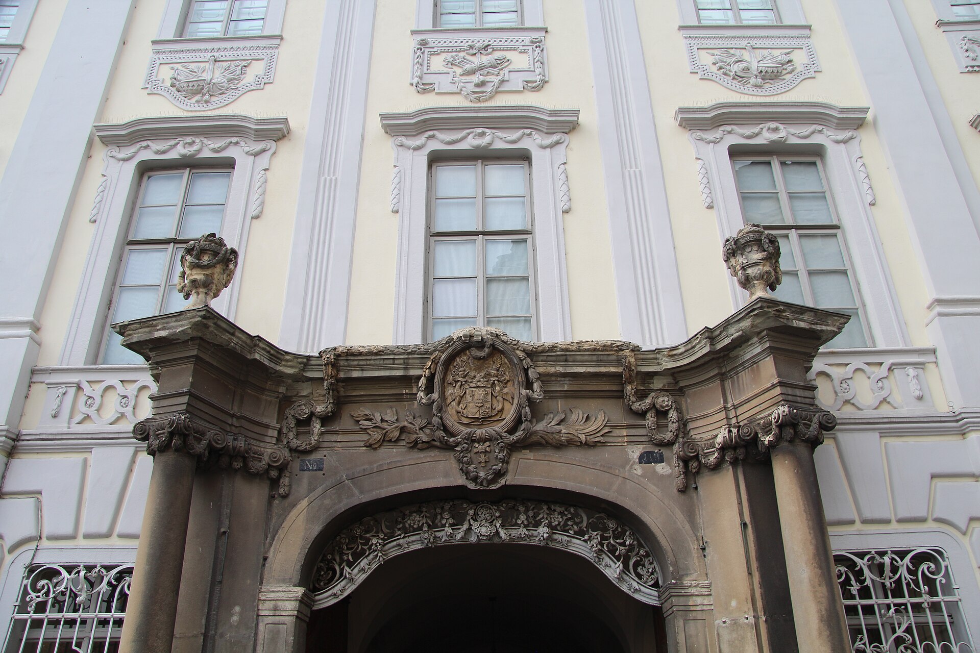 Partea superioară a portalului: blazon, cornișă și ferestre