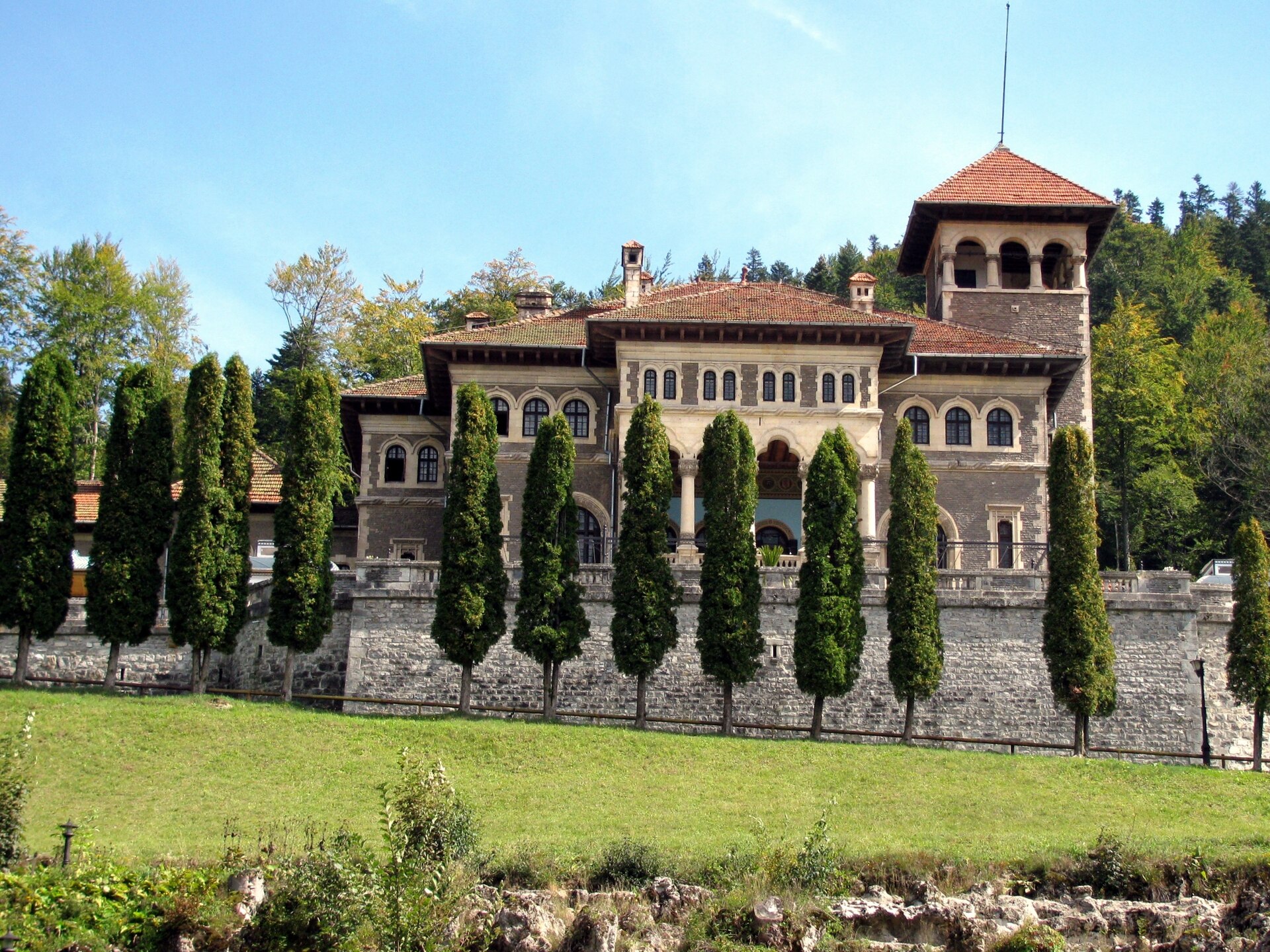 Fațada principală și turnul privite din parc, prin vegetație