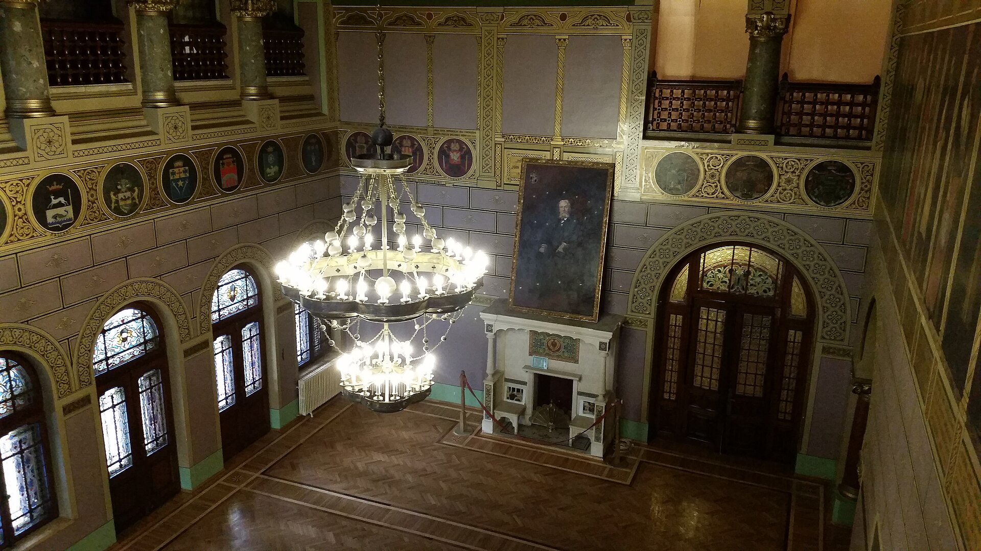 Sala reprezentativă văzută de la galerie: candelabru, ferestre și șemineu