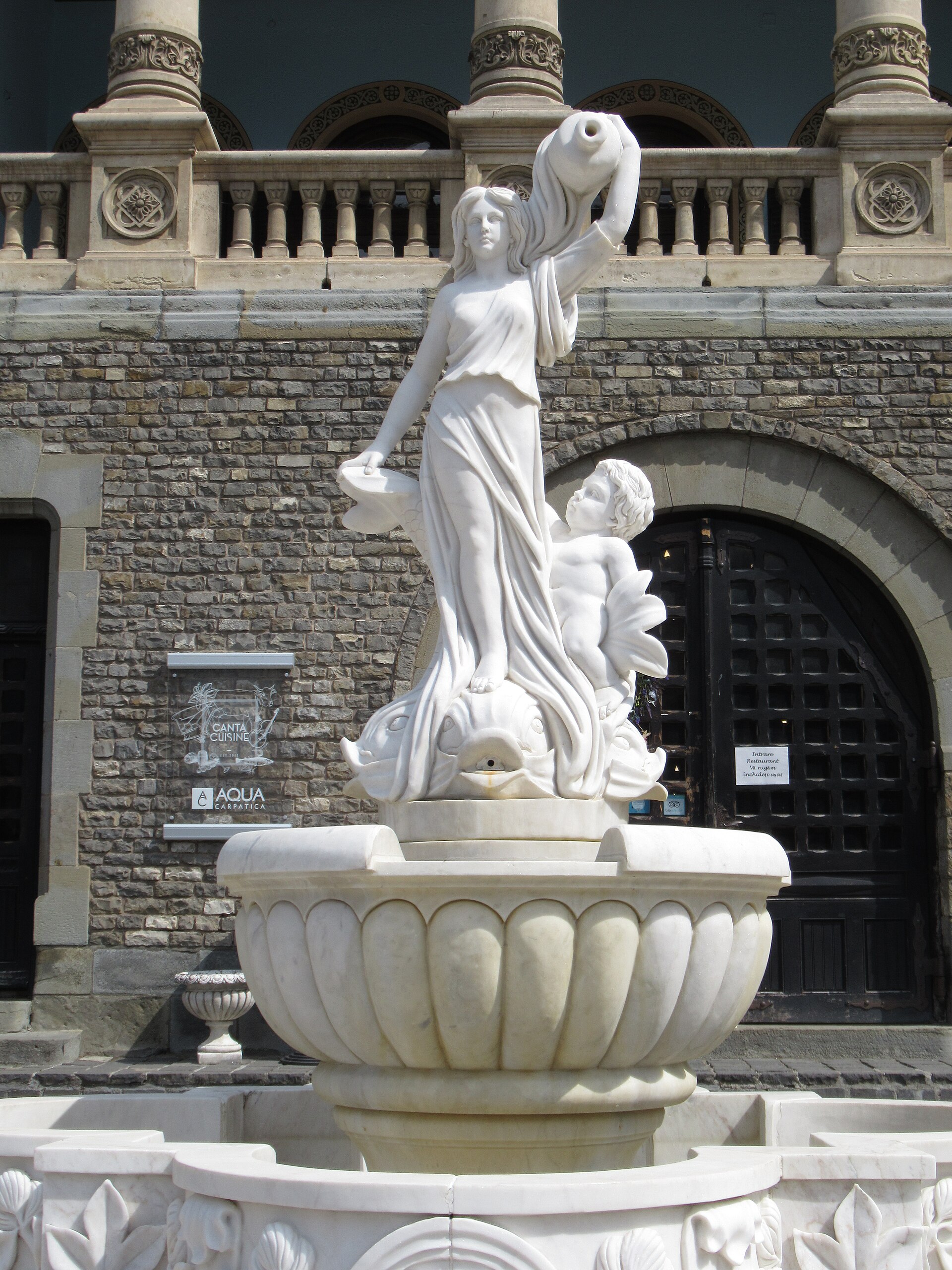 Sculptură și soclu ornamental în fața unei arcade de acces