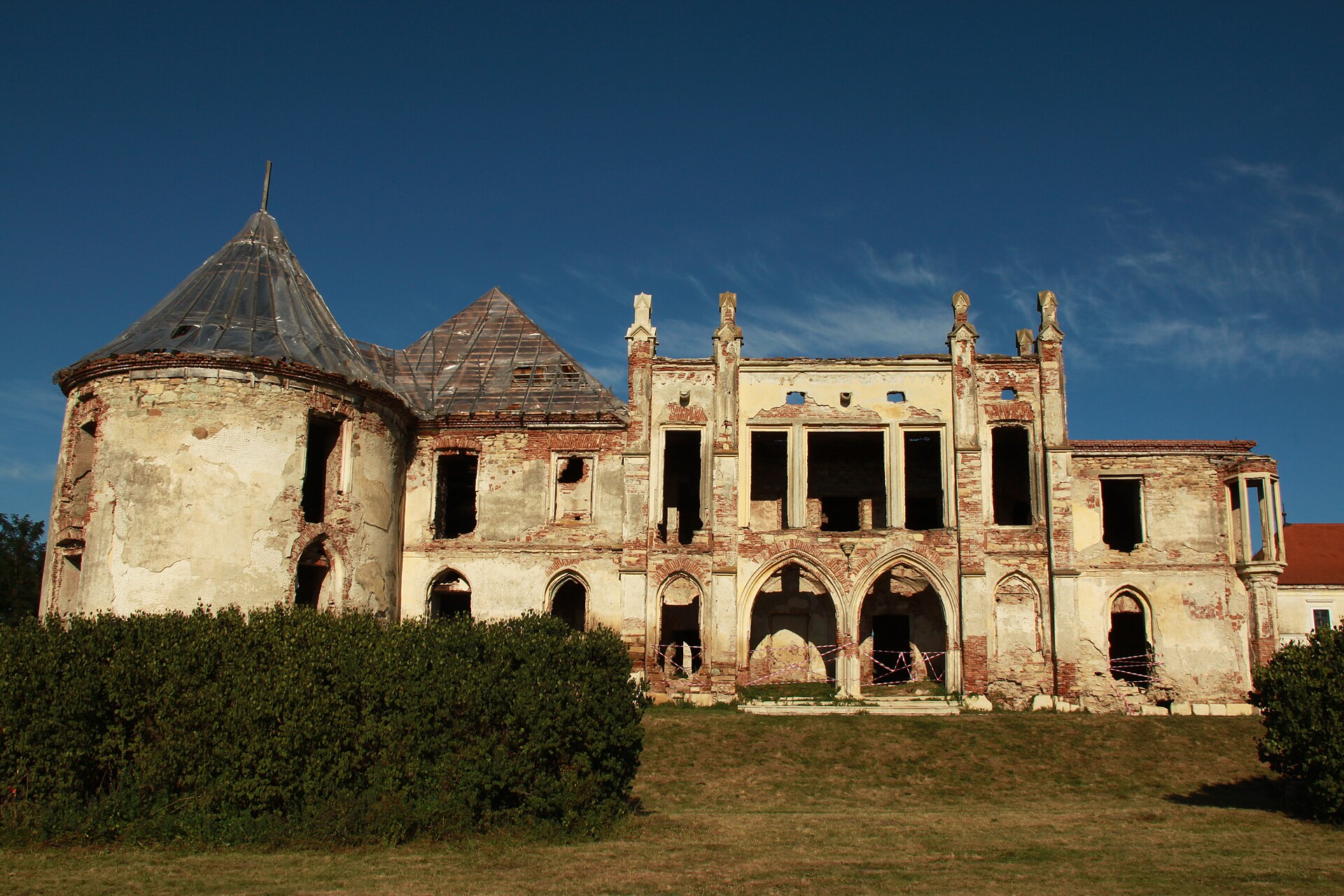 Fațada neogotică a clădirii principale, arcadele și turnul circular, vedere oblică de la sol.
