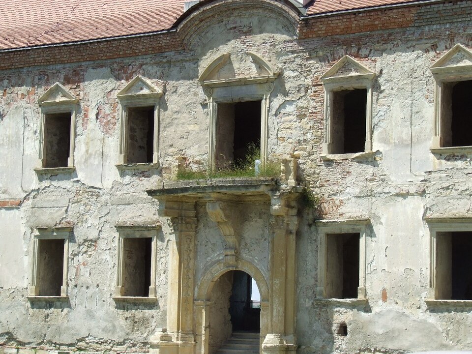 Balconul central, portalul de dedesubt și ferestrele laterale ale fațadei degradate.