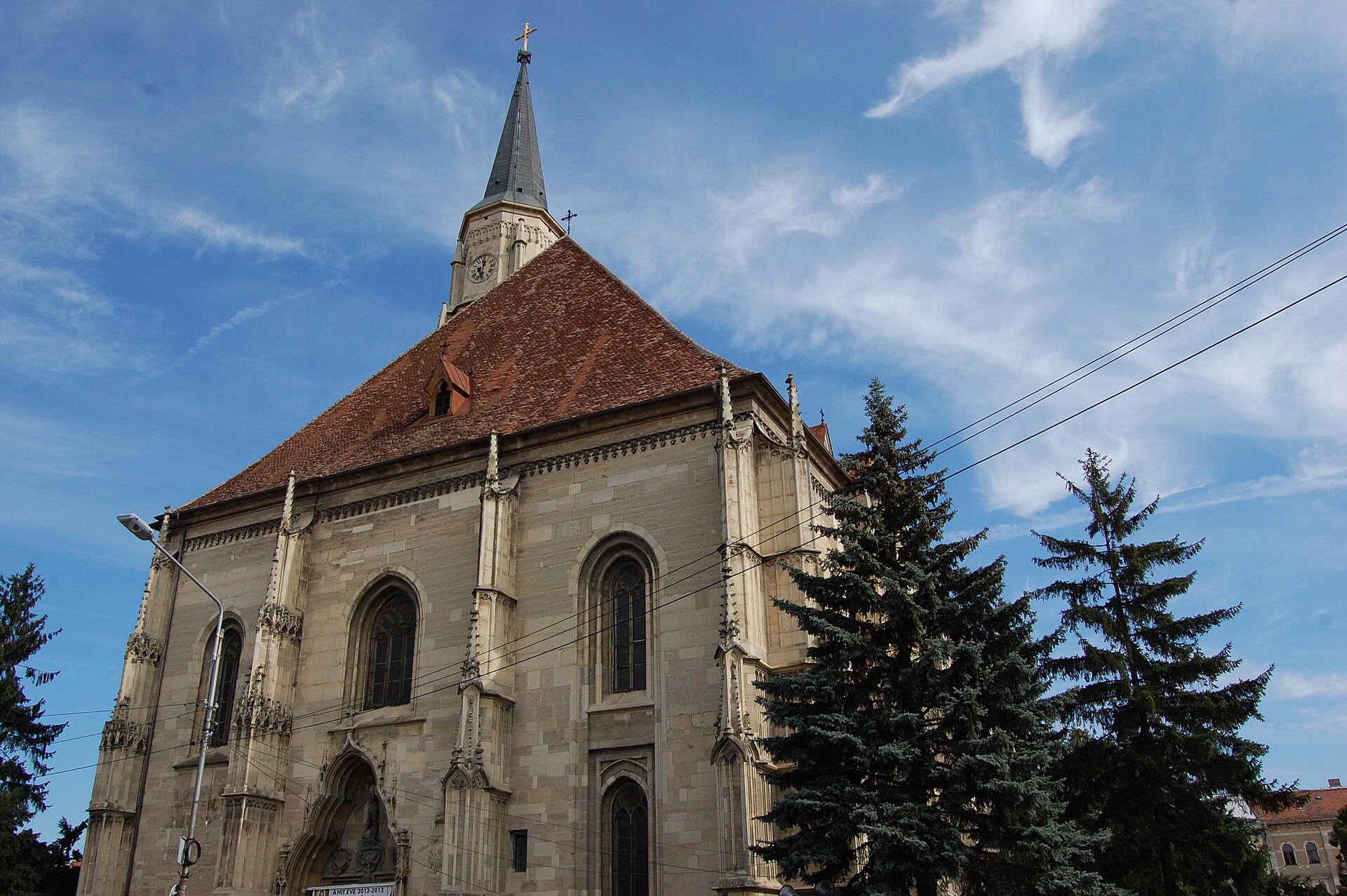 Fațada scurtă cu fronton, ferestre și contraforturi; turnul se vede dincolo de acoperiș.