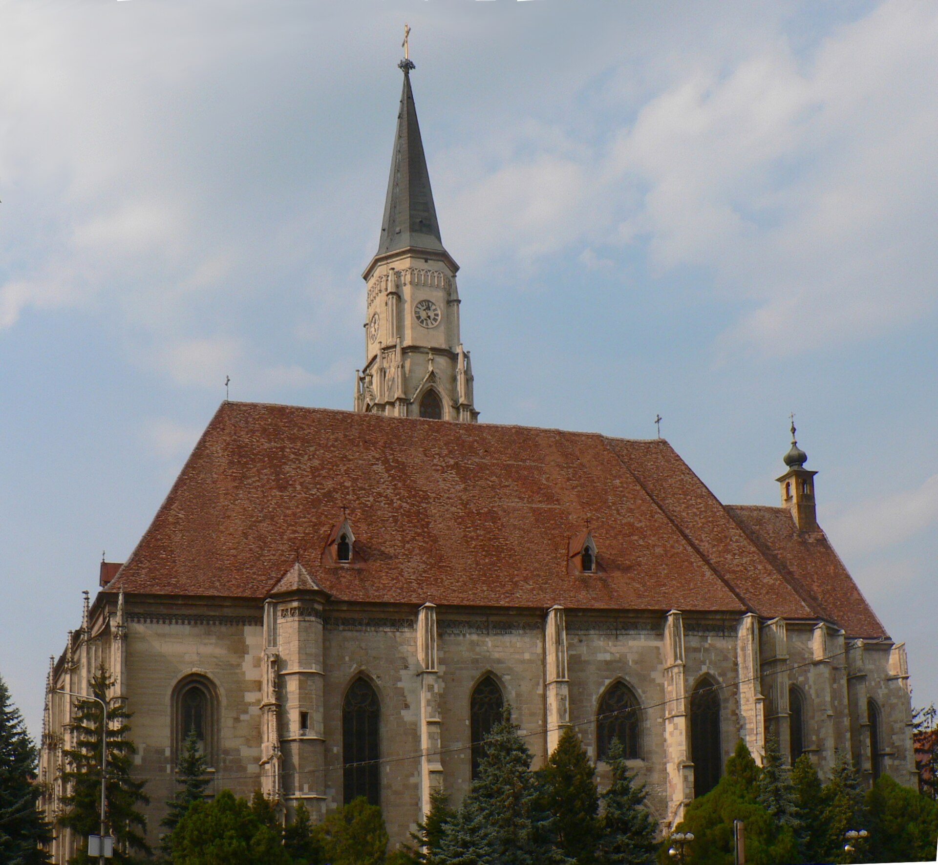 Fațada laterală și acoperișul lung, aproape frontal, cu ferestre și contraforturi.