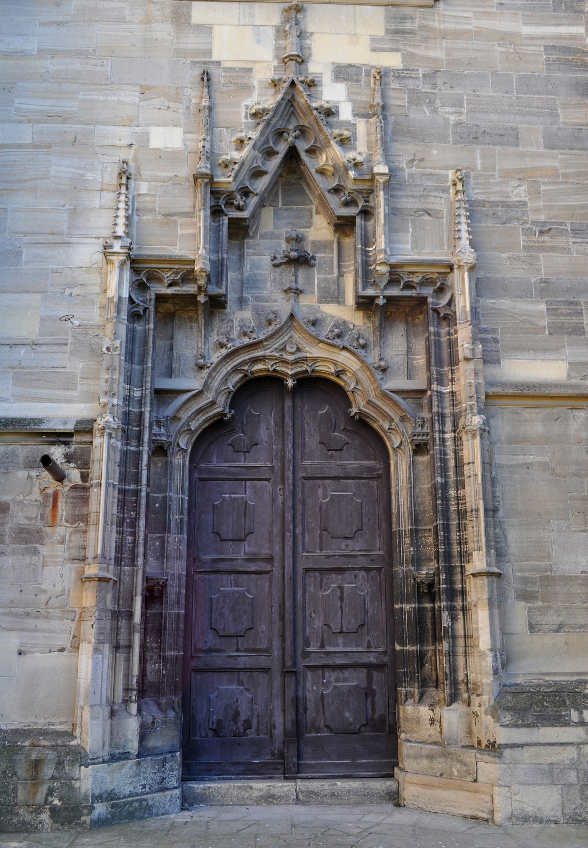 Portal gotic cu ușă închisă și ancadrament sculptat din piatră.