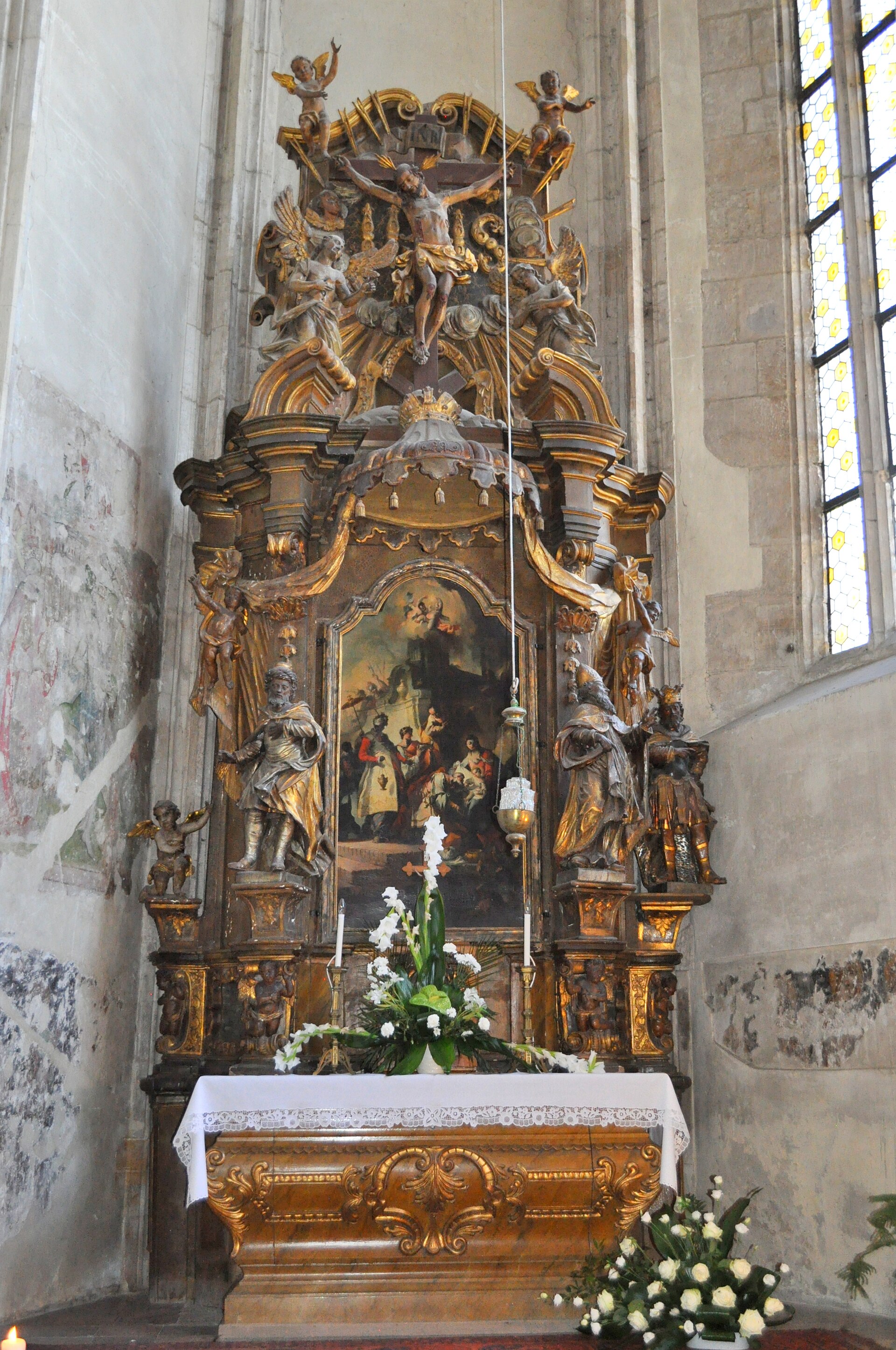 Altar lateral bogat decorat, în relație cu zidul și fereastra.