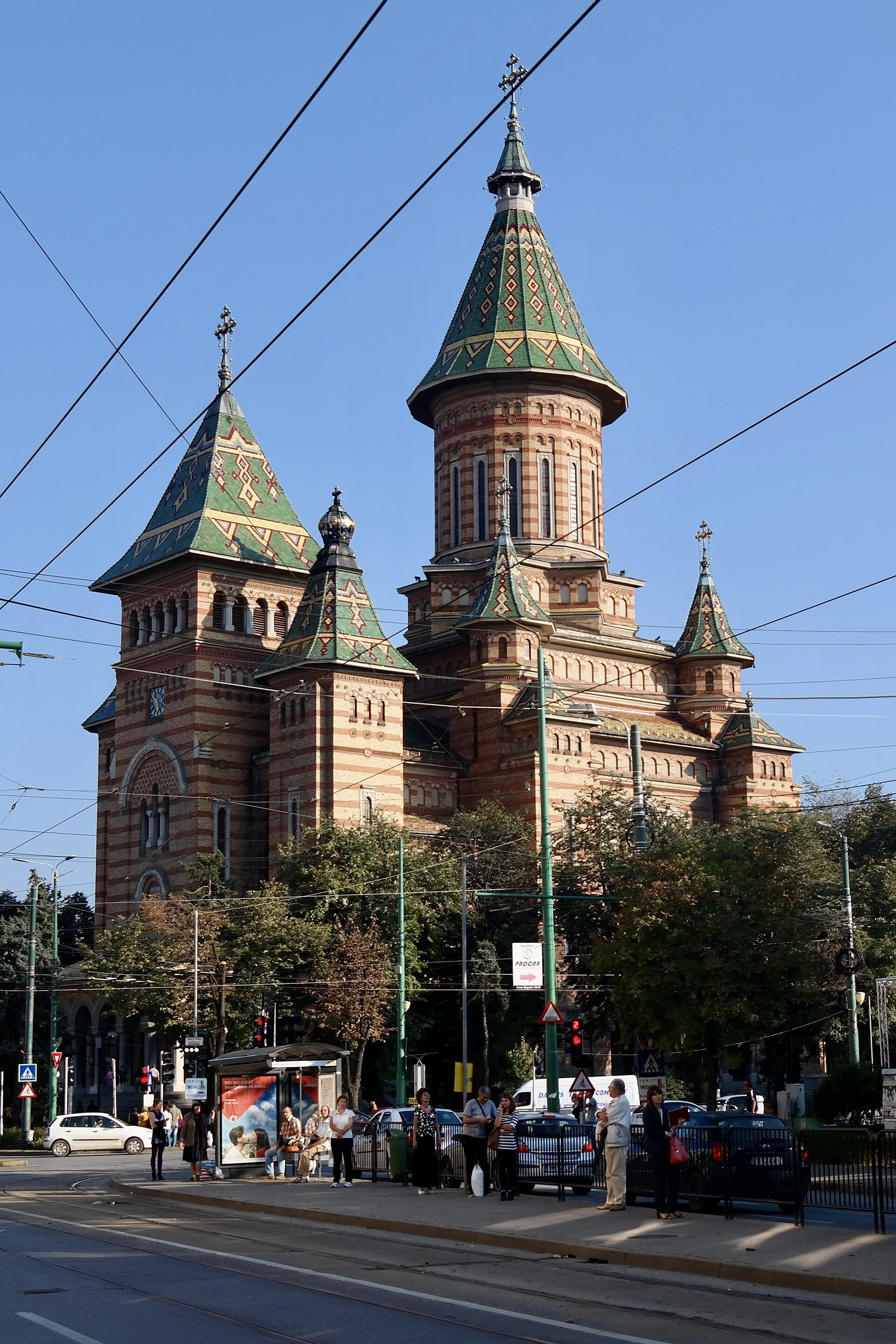 Catedrala mitropolitană română din Timișoara dinspre colț: turle, fațade de cărămidă și pridvor.