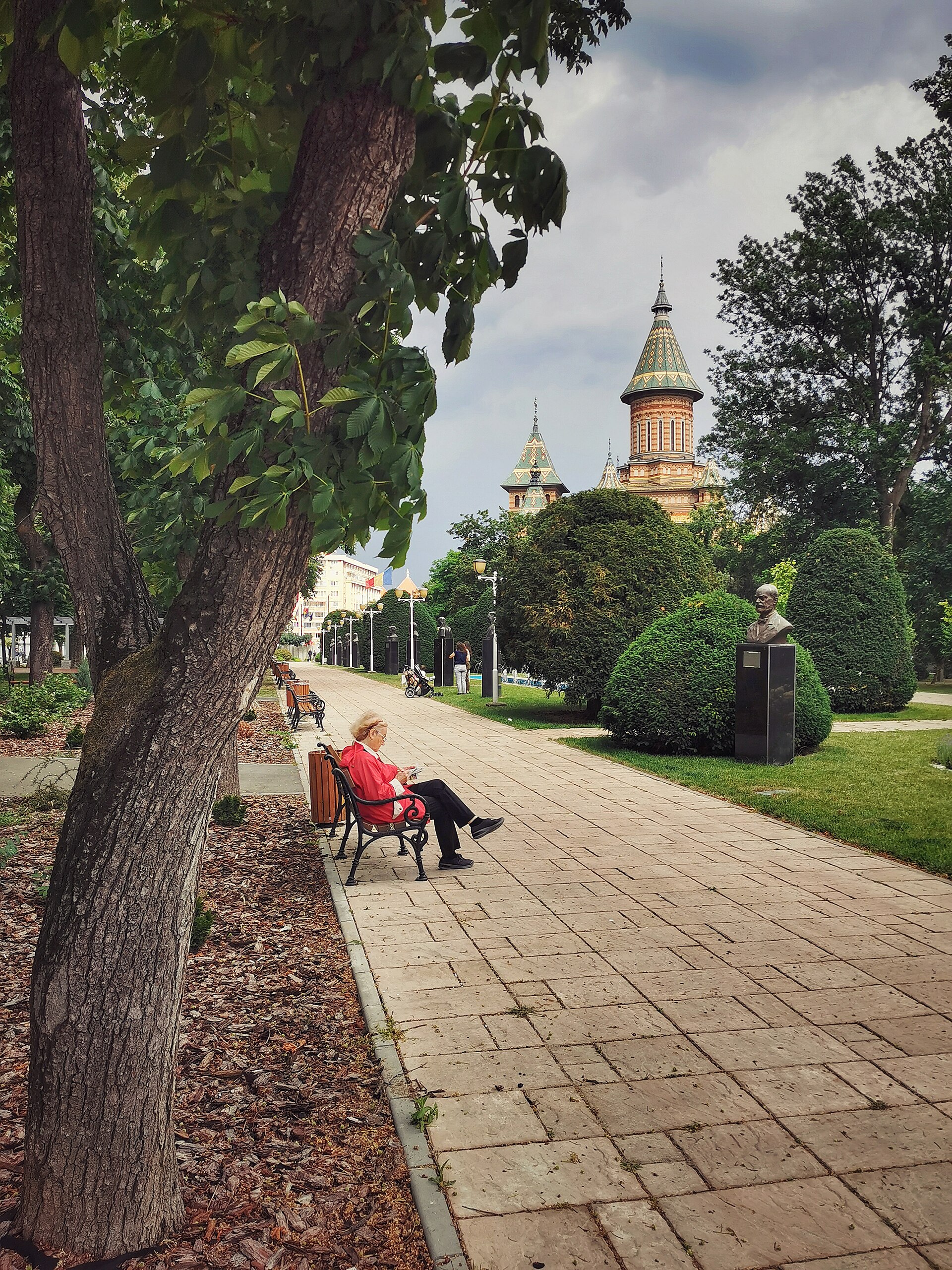 Turla și o parte a fațadei prin arborii parcului; baza clădirii este ascunsă.