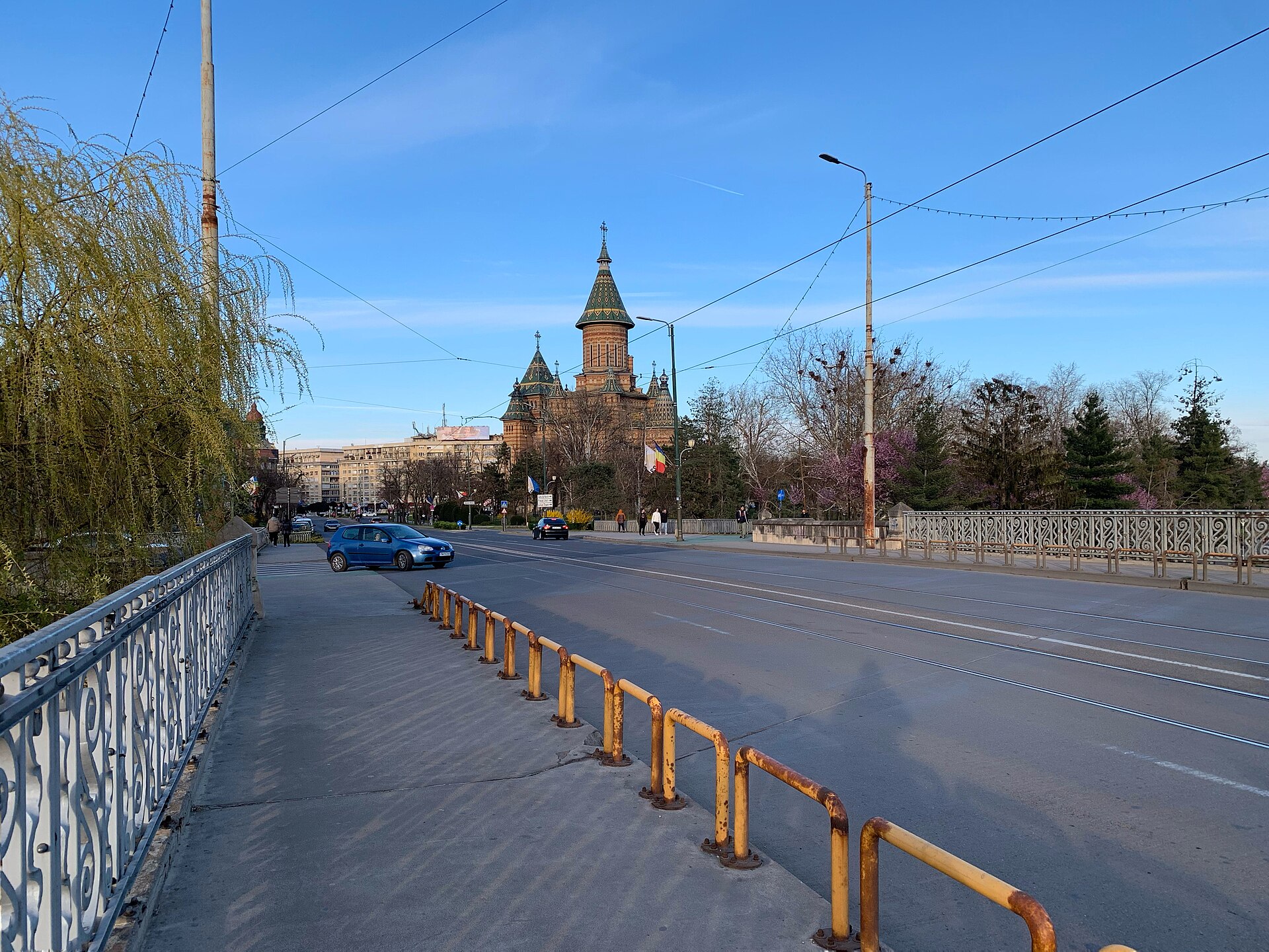 Catedrala dinspre Podul Traian: latura și turlele apar peste arbori și traficul stradal.