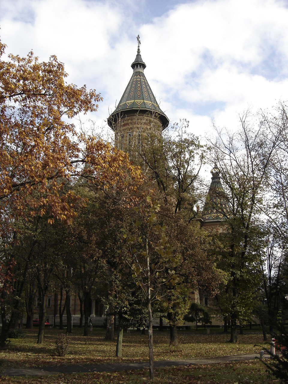 Turlele și învelitorile printre arbori fără frunziș; suprafețele joase rămân ascunse.
