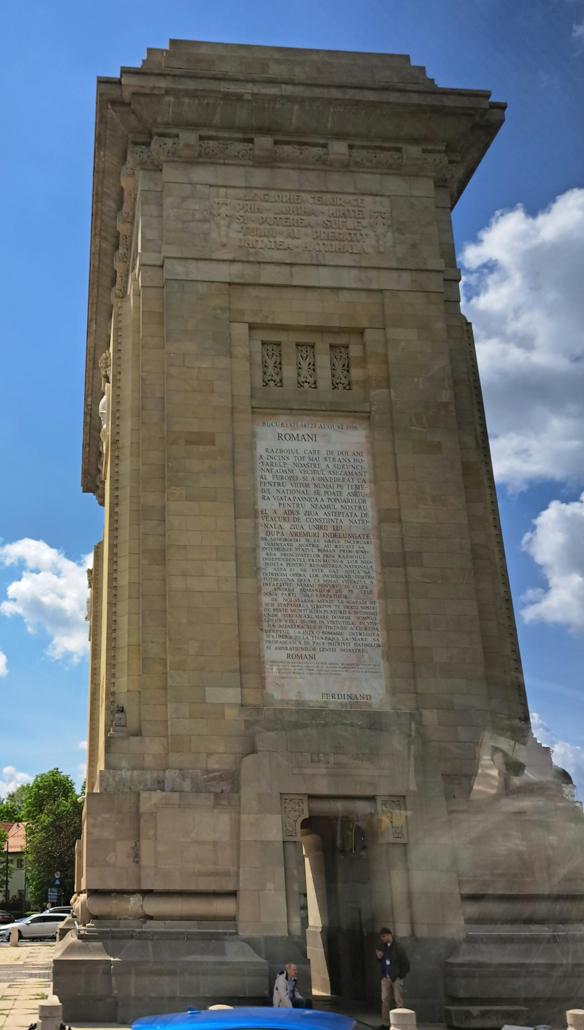 Fațada laterală a arcului, în perspectivă joasă: cornișă, inscripție și placaj de piatră.