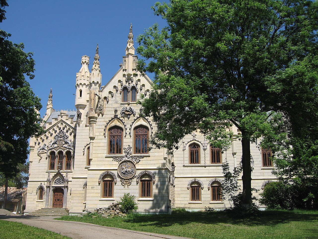 Fațada principală neogotică, frontonul și aripile joase, vedere din parc.