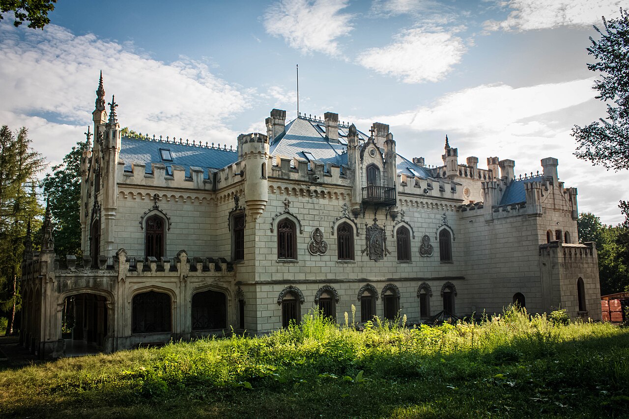 Fațada lungă cu ferestre ogivale, nivel inferior arcuit și coronament crenelat.