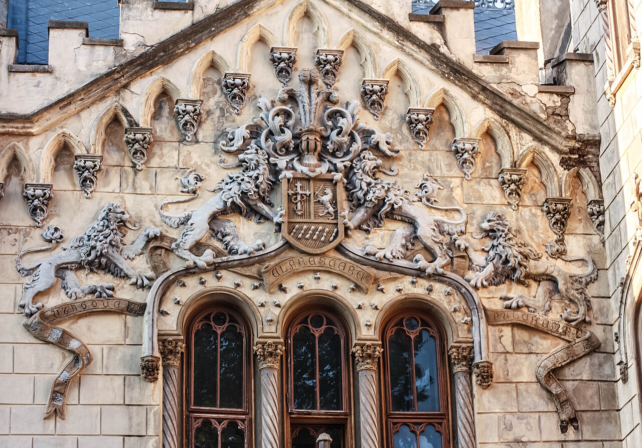Frontonul bogat sculptat, ferestrele și portalul intrării principale.