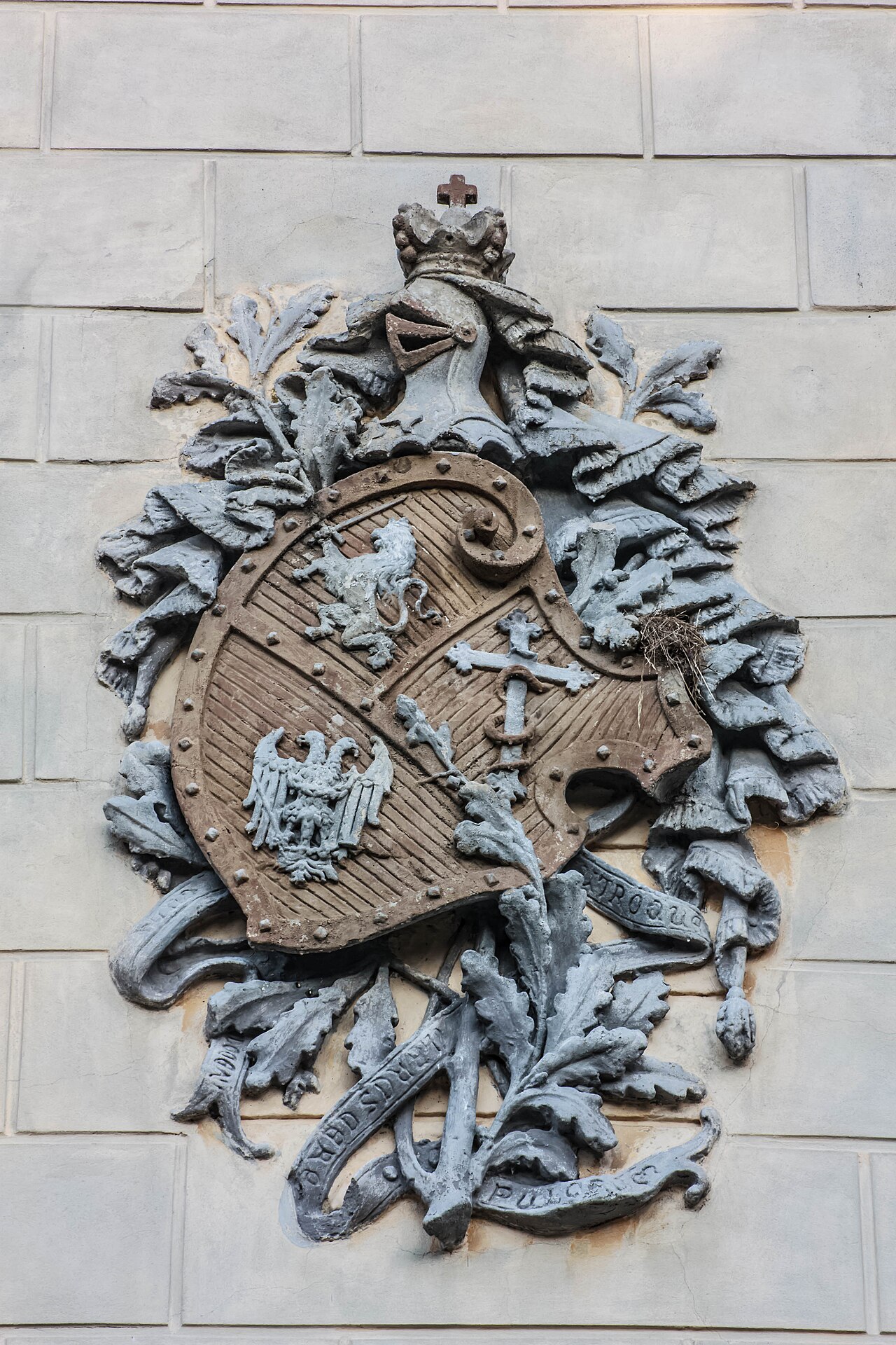 Stemă sculptată și ornament vegetal în relief pe fațadă.
