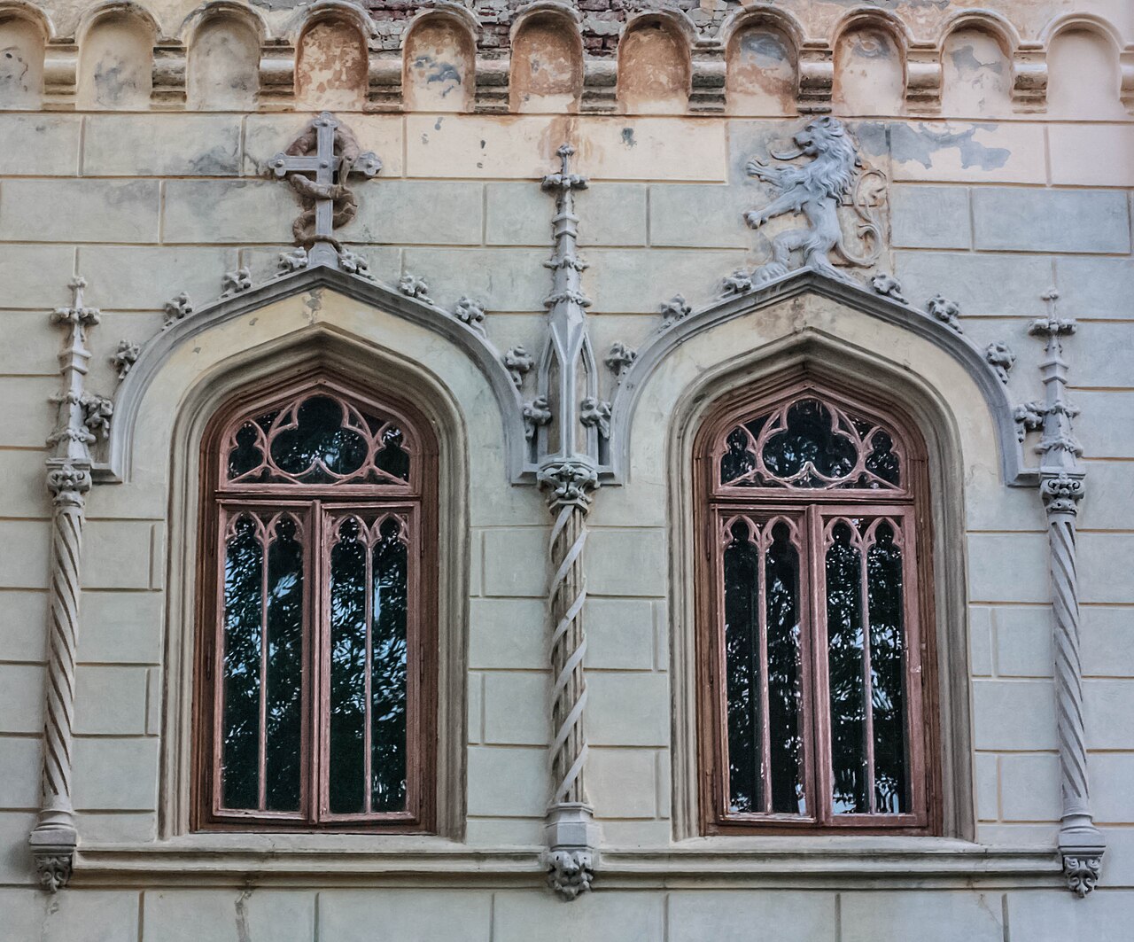 Două ferestre ogivale, ancadramente și registrul crenelat superior.